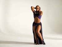 a woman in a purple dress is posing in front of a white background