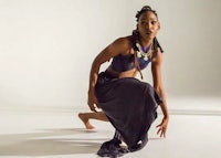 a woman in a black skirt is crouching in front of a white background