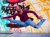 a woman is jumping in front of a graffiti wall