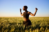 a woman standing in a wheat field with her arms outstretched
