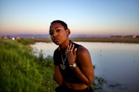 a woman is posing in front of a body of water