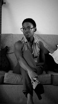 a black and white photo of a woman sitting on a couch with a guitar
